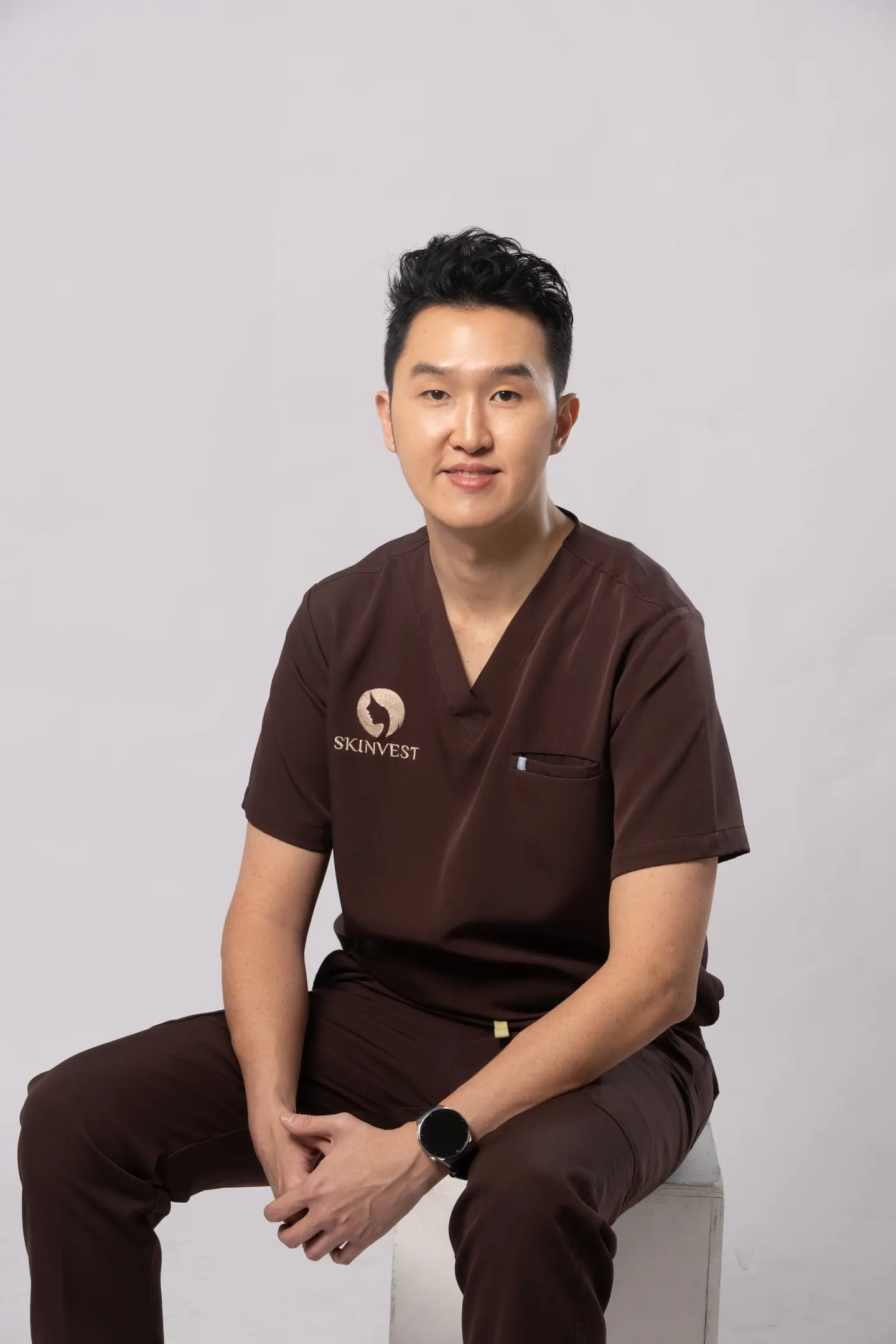 Foto dr. Adrian Aries, Dipl. AAAM mengenakan scrub cokelat Skinvest
