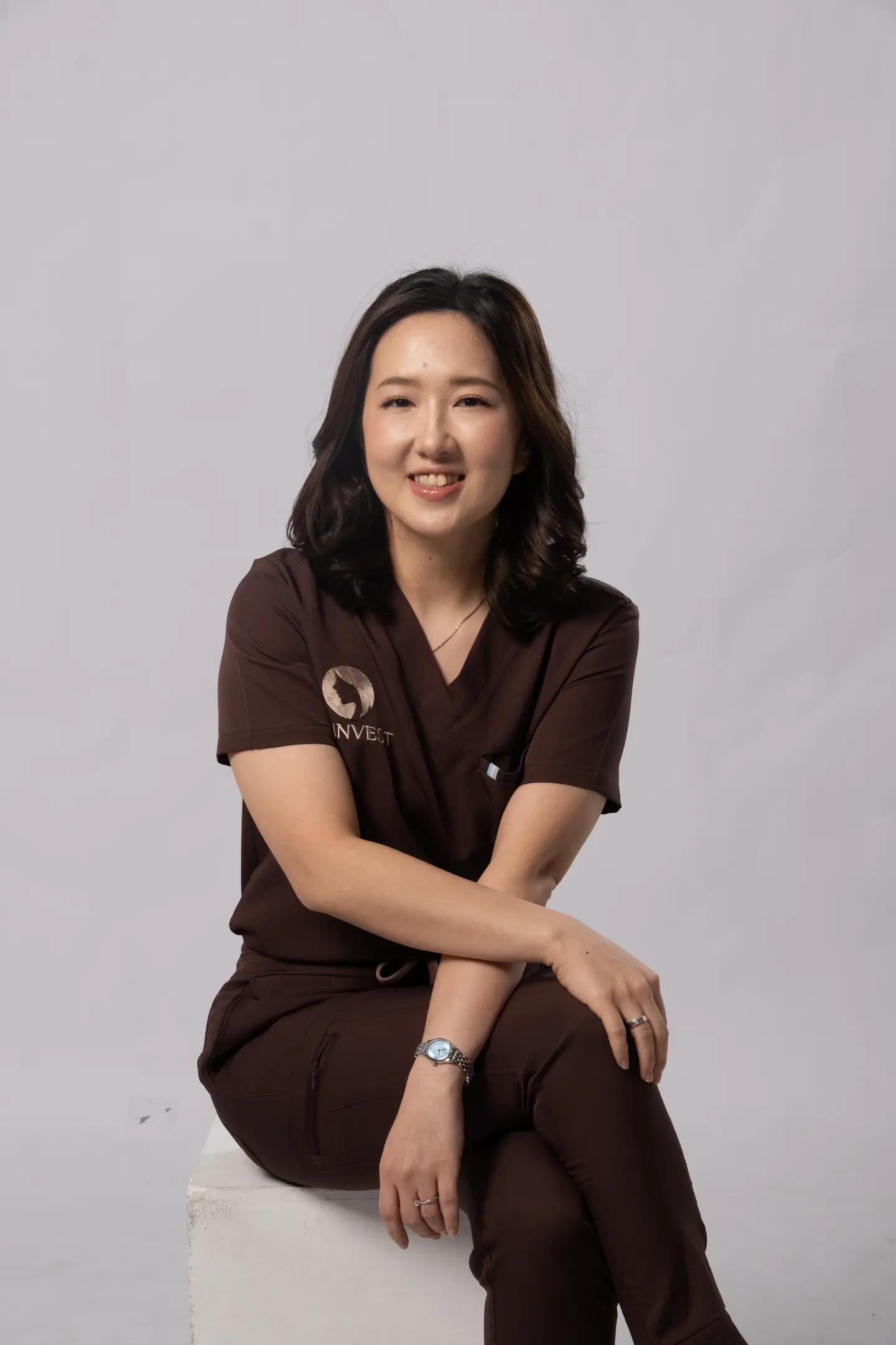 Foto dr. Devi Eliani Chandra mengenakan scrub cokelat Skinvest