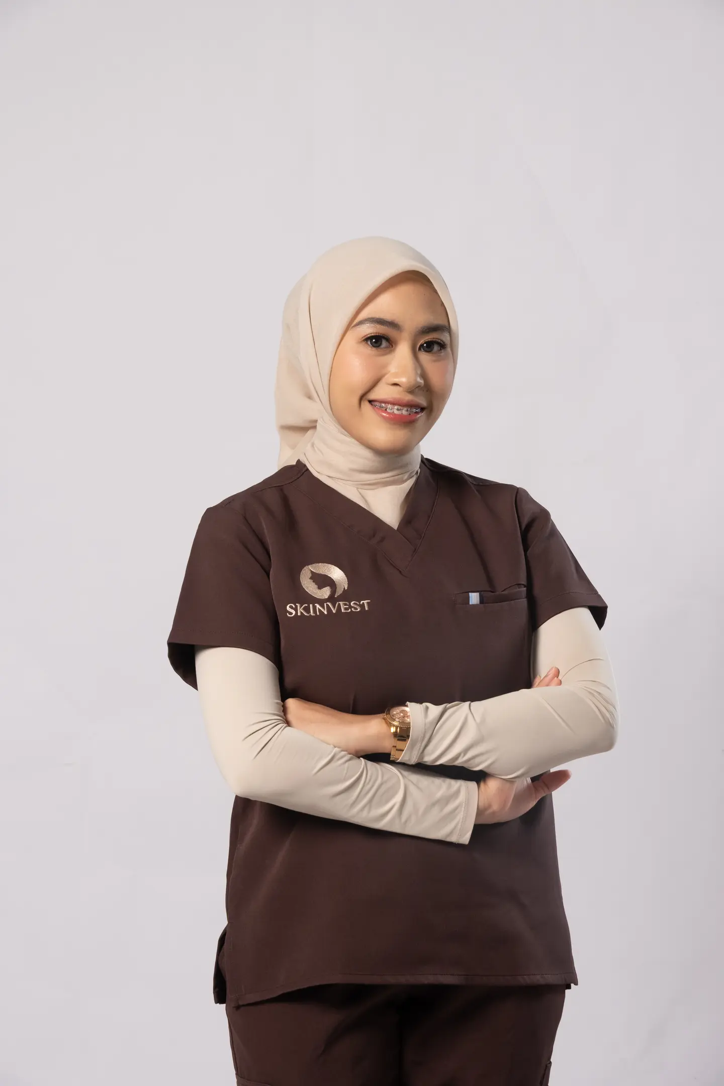 Foto dr. Nila Cindy mengenakan scrub cokelat Skinvest